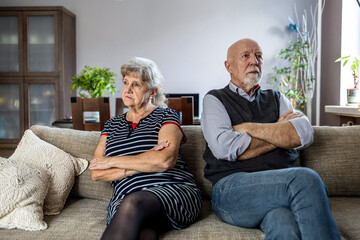 Senior couple sitting on sofa at home having a relationship problems
