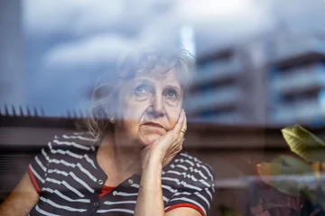 Foto op Plexiglas Portrait of senior woman looking through window   © pikselstock