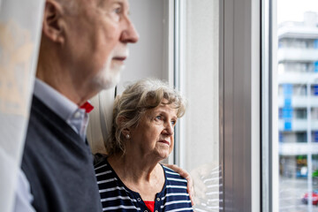 Portrait of senior couple looking out the window at home
