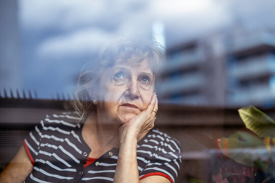 Portrait Of Senior Woman Looking Through Window 
