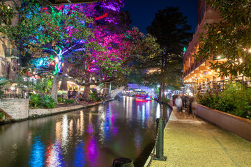 San Antonio River Walk by night with illuminated trees and restaurants. City park and pedestrian...