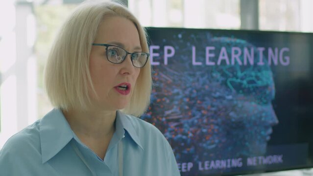 Medium close-up shot of Caucasian woman in formalwear telling to audience about new research in deep learning field