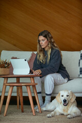Concentrated woman working on tablet with her dog lounging nearby