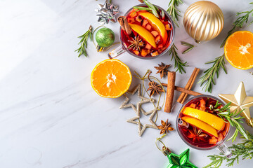 Traditional Christmas aromatic mulled wine cocktail, red wine grog tea drink with spices, cinnamon, orange and rosemary sprig, on Christmas New Year decorated wooden cozy background