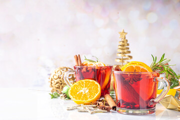 Traditional Christmas aromatic mulled wine cocktail, red wine grog tea drink with spices, cinnamon, orange and rosemary sprig, on Christmas New Year decorated wooden cozy background