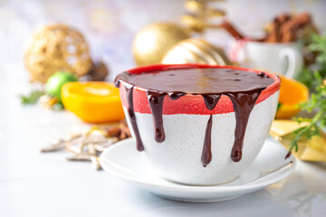Winter aromatic hot chocolate cup with Christmas background. Mug of dark hot cocoa drink with cinnamon, anise, spices and marshmallow, on cozy Christmas and New Year holiday decorated background 