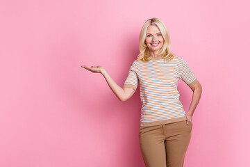 Portrait of nice woman with stylish hairdo wear trendy clothes palm demonstrate empty space proposition isolated on pink color background