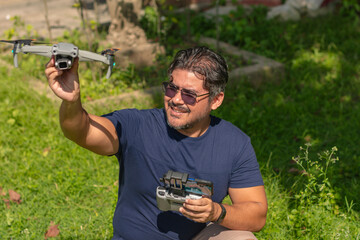A middle aged man crouches down prepares to launch a small aerial drone from his hand.