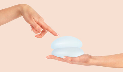 Female hand pointing on breast implants, mammoplasty. Copy space