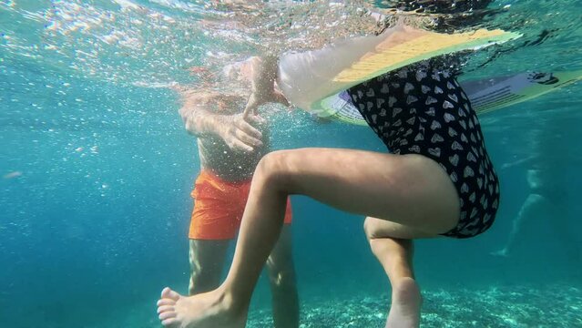 Dad teaches his daughter to swim in the sea. Underwater shooting.