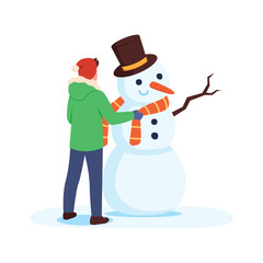 Boy in warm clothes makes a snowman with a carrot nose, scarf and top hat
