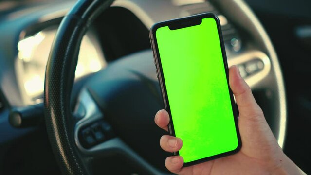 Hand using phone green screen in car, holding smartphone at car, mobile phone in hand 