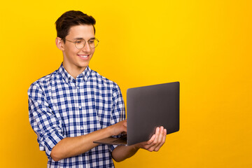 A man holds a laptop in his hands while standing, working on a PC, typing on a keyboard