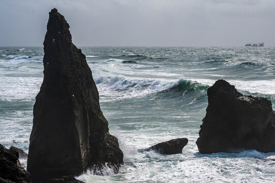 Rock formation on reykjanes peninsula on iceland with waves and a ship in the background- valahnúkamöl