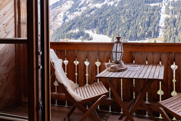 Cozy wooden balcony of the hotel room with folding furniture, mountain view with ski lift, Austria