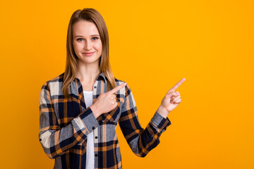 Attractive smiling young woman finger idicating new product sale presentation isolated over yellow studio wall