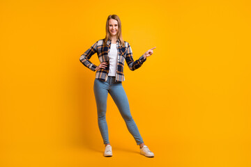 Fototapeta na wymiar Attractive smiling young woman finger idicating new product sale presentation isolated over yellow studio wall
