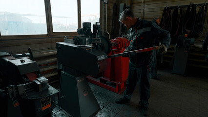 Man worker polishing the steel pipe at a factory workshop. Creative. The metal details plant processing.