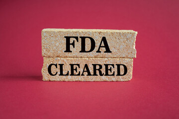 FDA, Food Drug Administration cleared symbol. Concept words FDA cleared on brick blocks on a beautiful red background. Business and FDA, Food Drug Administration cleared concept.