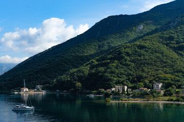 Fototapeta na wymiar nature landscape of Boka Kotorska Bay in Montenegro, stunning green mountains, adriatic sea, stone houses, sailing boats, calm water with reflections