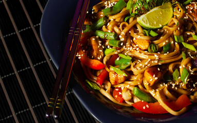 Udon noodles with paprika with sticks of Japanese cuisine, hot plate with udon noodles.