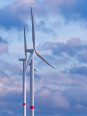 Two wind turbines against the cloudy sky