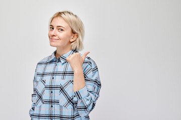 Young blond woman in casual pointing aside finger, demonstrating empty space for product or text...