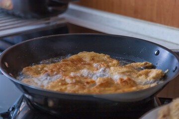 Fried meat in a triple package in a pan.