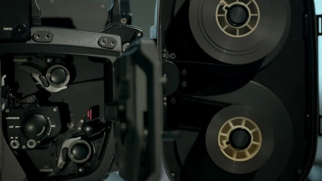 Film transport through sprockets and shuttle in a film gate. Closeup of 35 мм  professional film movie camera operation. 4k footage.  
