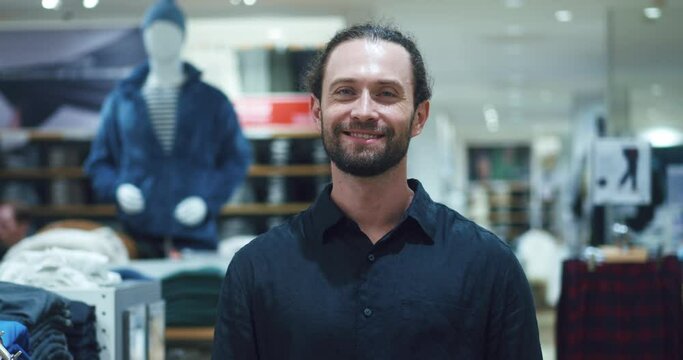 Portrait of male owner of fashion store .a bearded stylish man stands against the background of a clothing department in a trendy outfit in fashion store. black friday discount time in fashion store