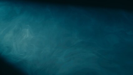 Abstract background of chaotically blending puffs of blue smoke on a black background. Realistic fog in blue neon light close up. Texture and abstract art. Copy space.