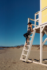 A beautiful athletic girl exercises on the beach near the sea in a black sportswear