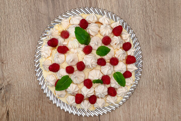 Raspberry cake with pudding and meringue, visible raspberries and mint leaves, view from above.
