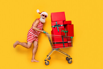 Full length photo of positive carefree senior guy dressed christmas swimwear buying xmas gifts...