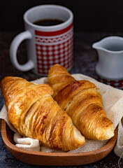 Fresh croissants in a wooden bowl and a cup of coffee