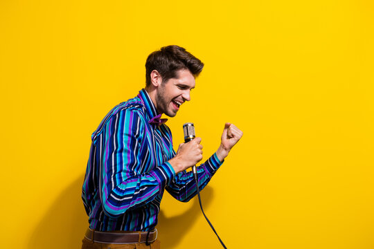 Portrait of satisfied guy dressed stylish shirt bow tie screming in microphone on stage isolated on vibrant yellow color background