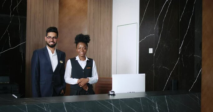 Portrait of polite, professional male and female workers of fancy hotel in uniform. Indian and African-American hotel managers smiling and looking into the camera. Customer care concept.