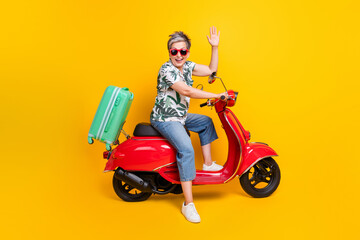 Full body photo of nice pensioner lady drive scooter travel wave hand wear trendy tropical print outfit isolated on yellow color background