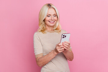 Portrait of positive person toothy smile use smart phone texting telegram instagram facebook isolated on pink color background