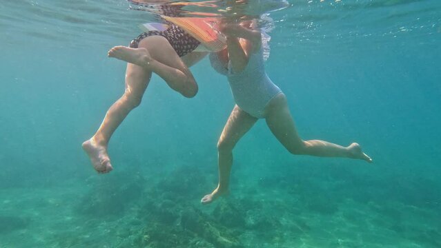 A woman and a child are swimming in the sea. Underwater photography.