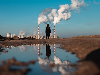 a girl stands against the backdrop of an electricity generation plant