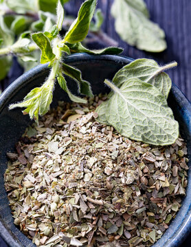Chopped dried oregano put in a ceramic bowl and fresh oregano leaves