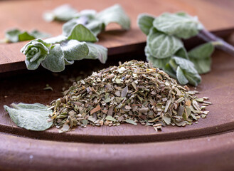 Chopped dried oregano and green oregano leaves on the wooden board