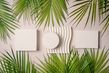 Decorative plaster podiums with palm leaves on pastel pink background, top view, flat lay. Place...