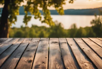 Fototapeten Empty wooden table top with blurred nature background Calm sunny evening in nature with view to lake or river © FrameFinesse