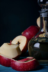 Fresh apples and apple vinegar in bootle on blue wooden background