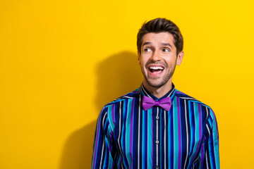 Obraz premium Portrait of ecstatic guy dressed stylish shirt bow tie staring at discount empty space isolated on vibrant yellow color background
