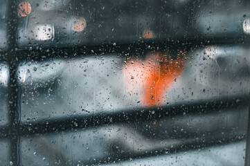 Raindrops on glass with blurred christmas tree in the background, blurred lights, rain concept.