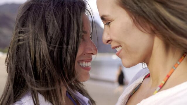 Gay lesbian female couple enjoy tender moment together outside with beach background. LGBTQ diversity and family love concept