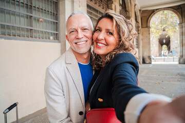 Affectionate mid adult married couple having fun taking a selfie portrait together on a romantic...